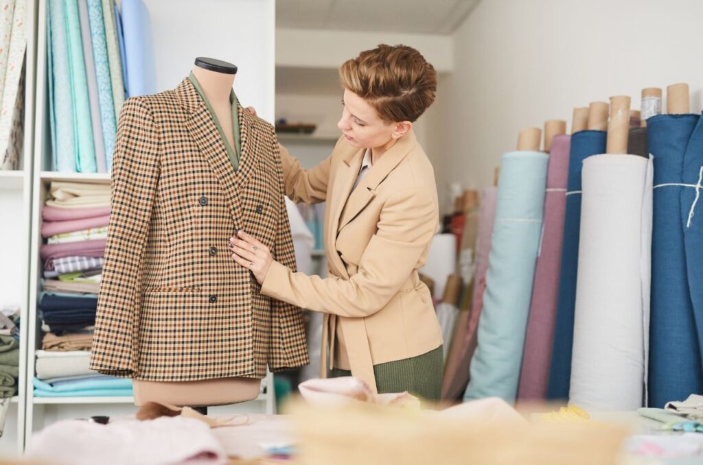 Plus-size senior sewist adjusting a tailored jacket on a dress form, representing longevity and expert craftsmanship.