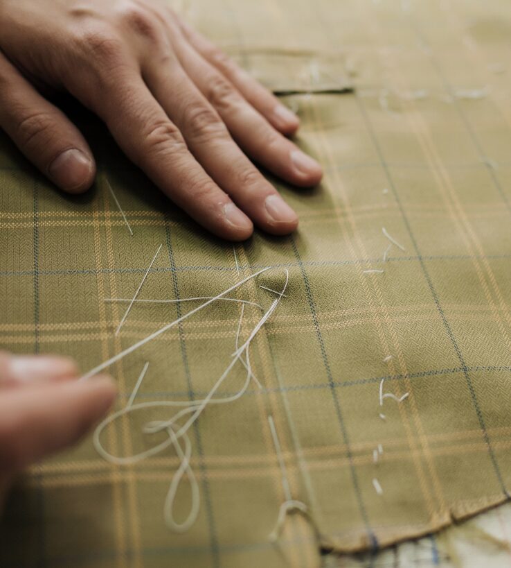 Close-up of hand stitching fabric, showcasing the art of classic tailoring and craftsmanship.