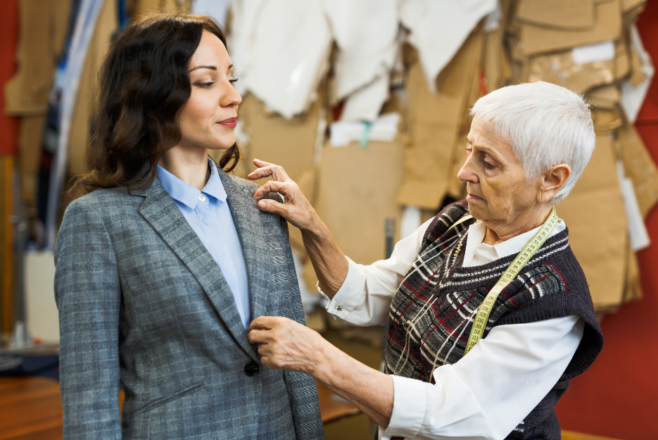 Two women fitting a tailored jacket on a dress form during a sewing session, showcasing classic plus-size tailoring techniques.