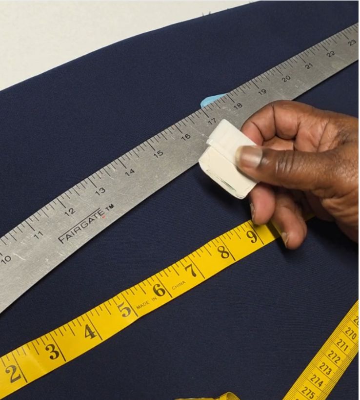 Hand marking fabric with tailor’s chalk, metal ruler, and measuring tape—copying fit from a garment.