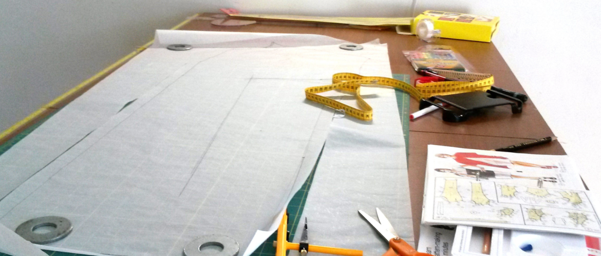 Sewing patterns, measuring tape, and tailoring scissors on a cutting table, demonstrating the Lutterloh fitting system.