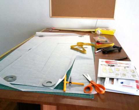 Sewing patterns, measuring tape, and tailoring scissors on a cutting table, demonstrating the Lutterloh fitting system.