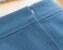 Close-up of a lapped zipper installed in blue fabric, showing the folded overlap and hidden stitching line