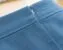 Close-up of a lapped zipper installed in blue fabric, showing the folded overlap and hidden stitching line